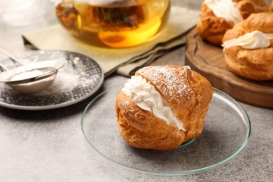 Photo of Delicious profiteroles filled with cream on grey table, space for text