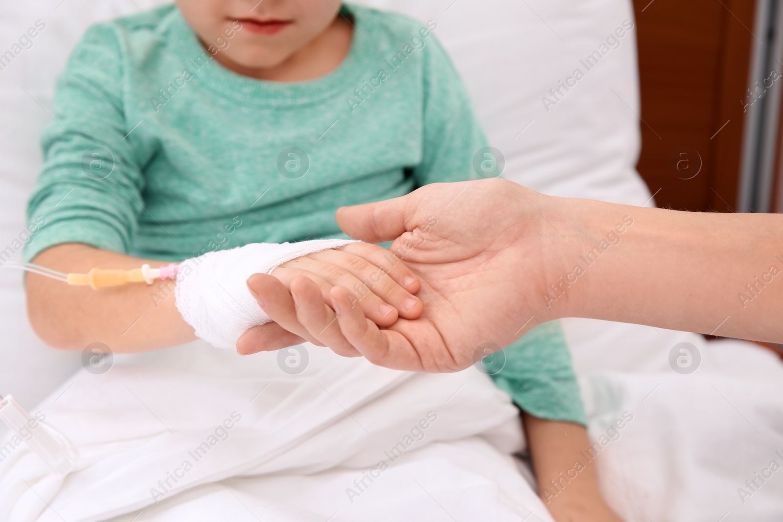 Photo of Woman visiting her little child with intravenous drip in hospital, closeup