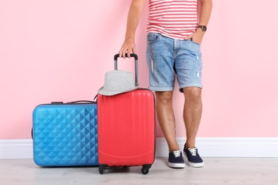 Photo of Man with suitcases near color wall. Vacation travel