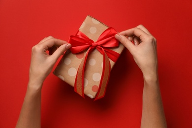 Photo of Woman with Christmas gift on red background, top view