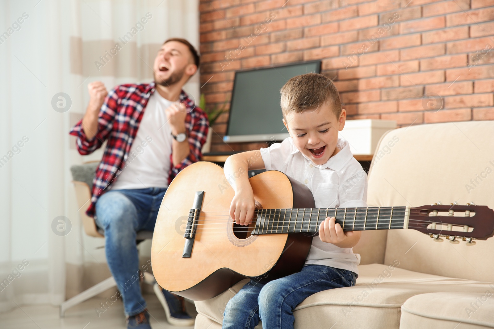 Photo of Father and son playing guitar and singing at home