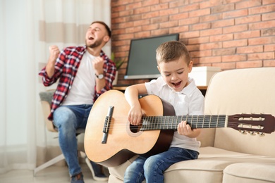 Photo of Father and son playing guitar and singing at home