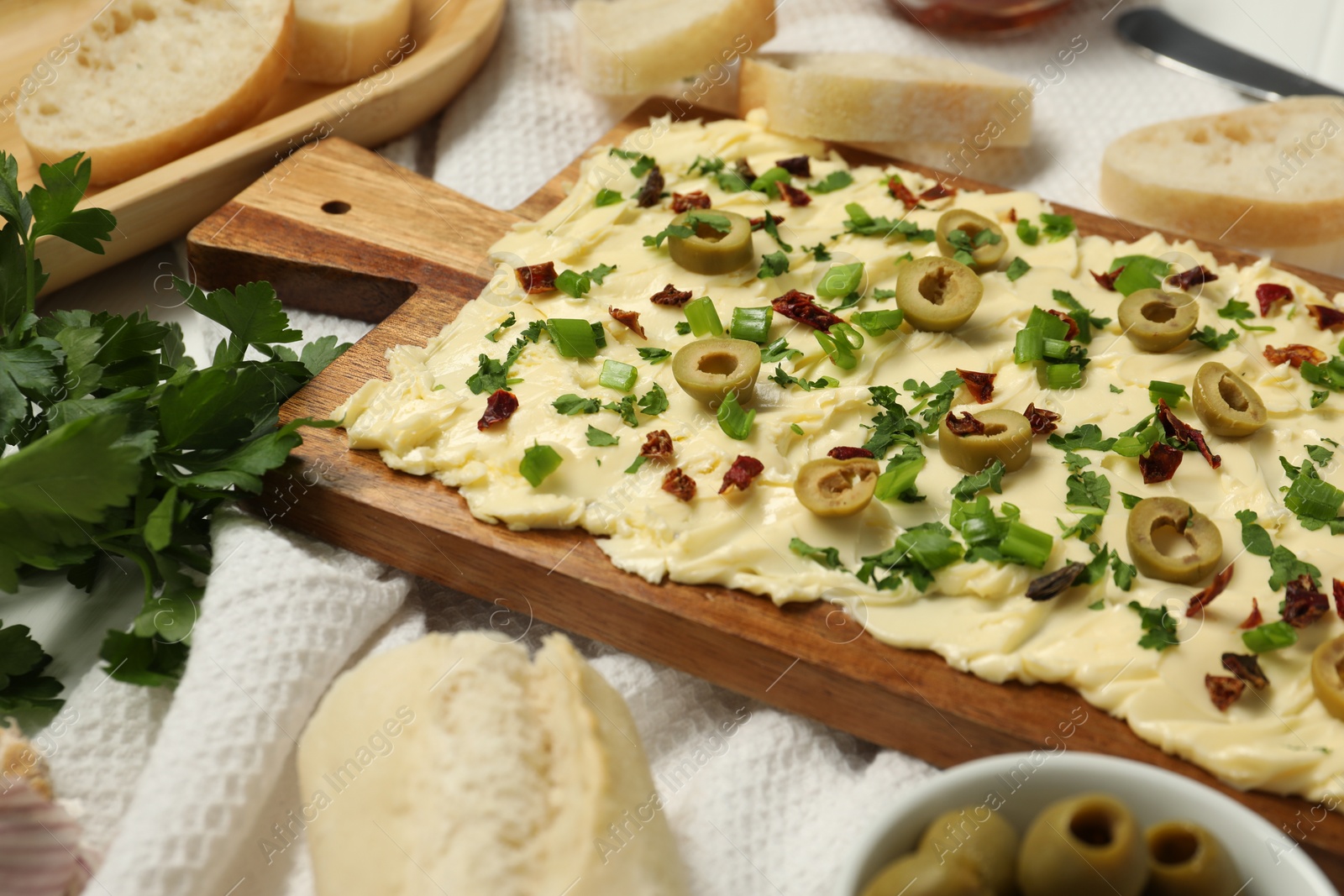 Photo of Fresh butter board with cut olives, onion and sun-dried tomatoes on table