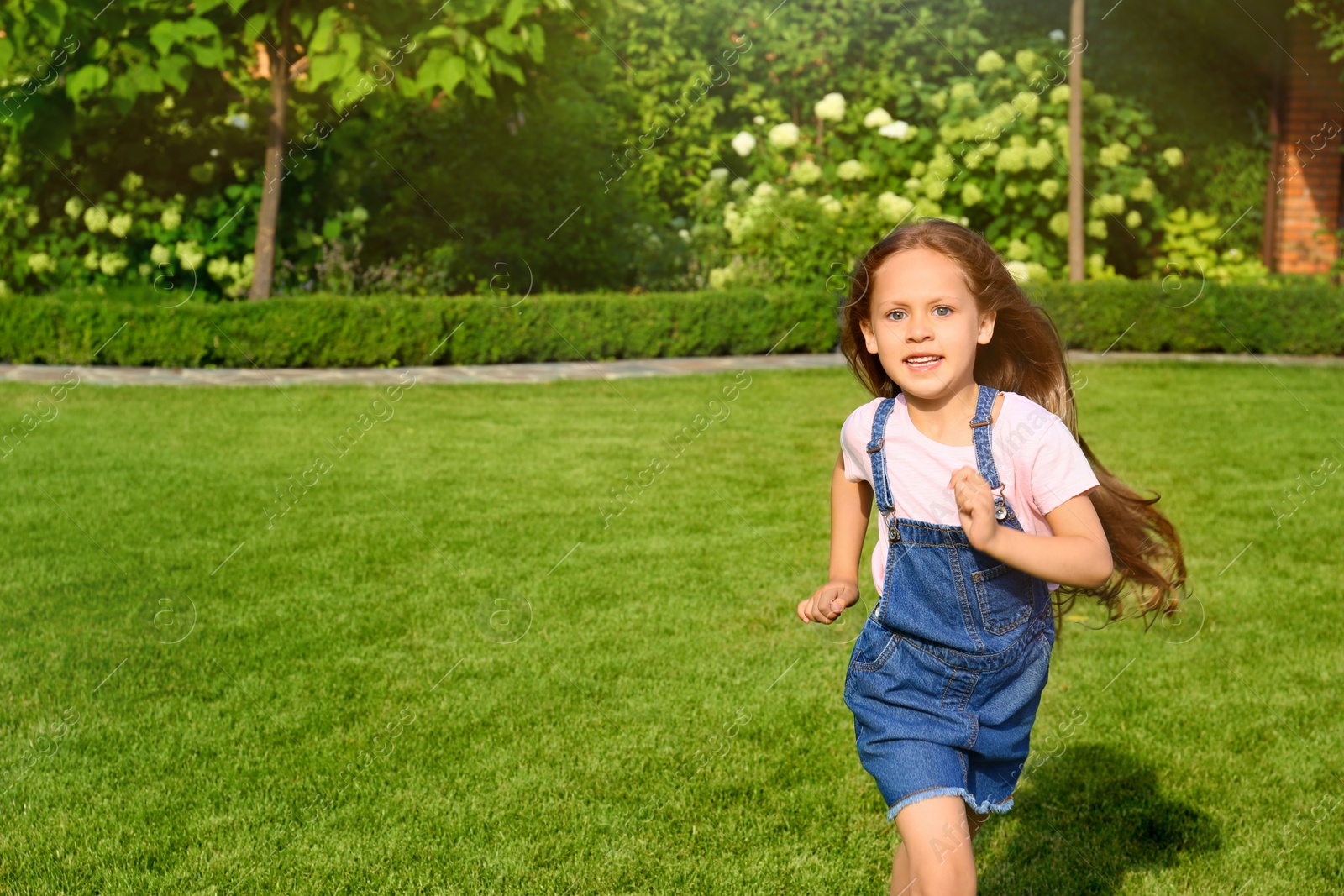 Photo of Cute little girl running in green park on summer day