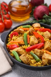 Delicious rice and chicken served with vegetables on light grey table
