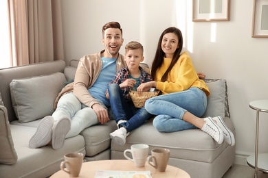 Happy family watching TV on sofa at home