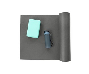 Grey exercise mat, yoga block and bottle of water isolated on white, top view