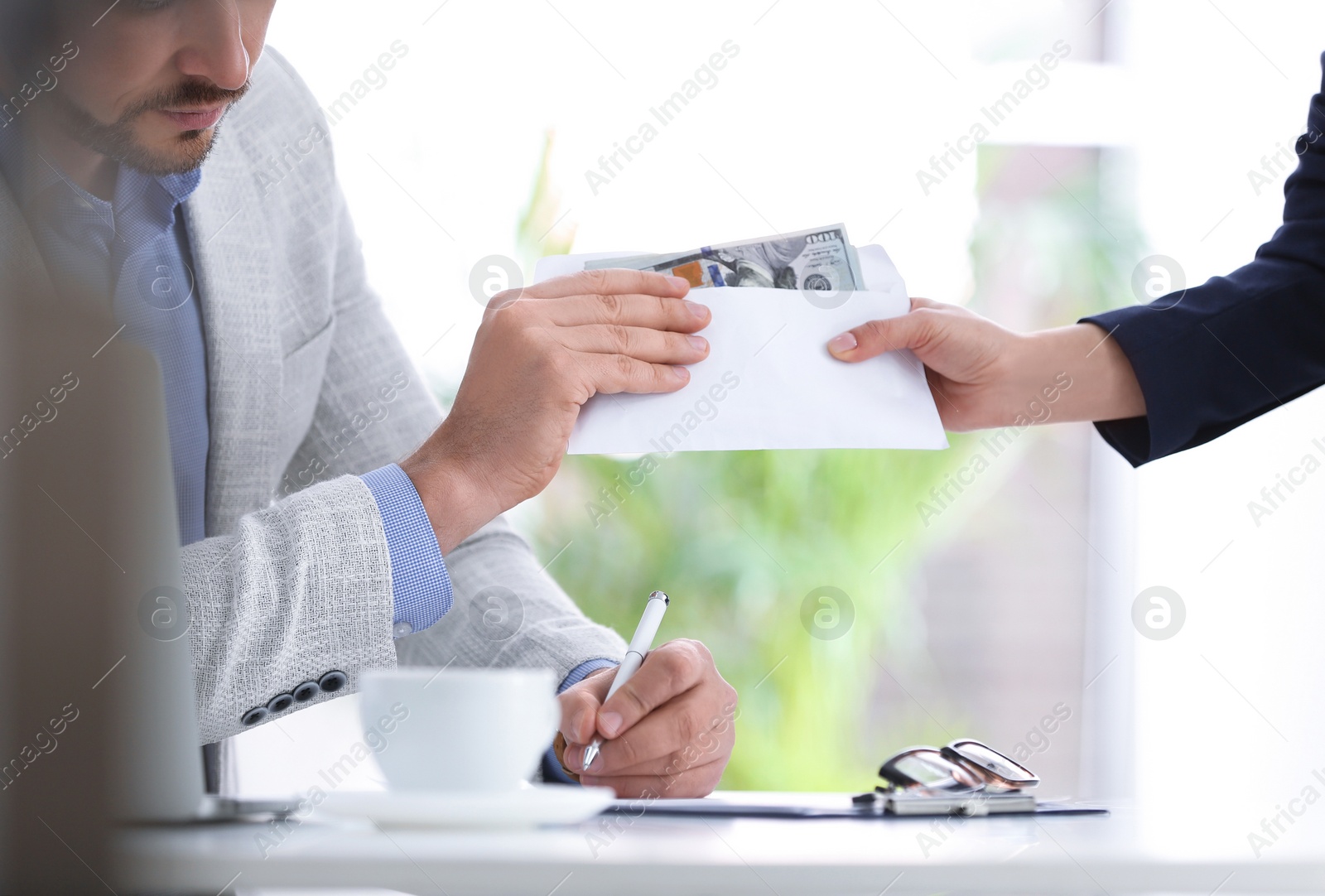 Photo of Woman giving bribe to man at table indoors, closeup