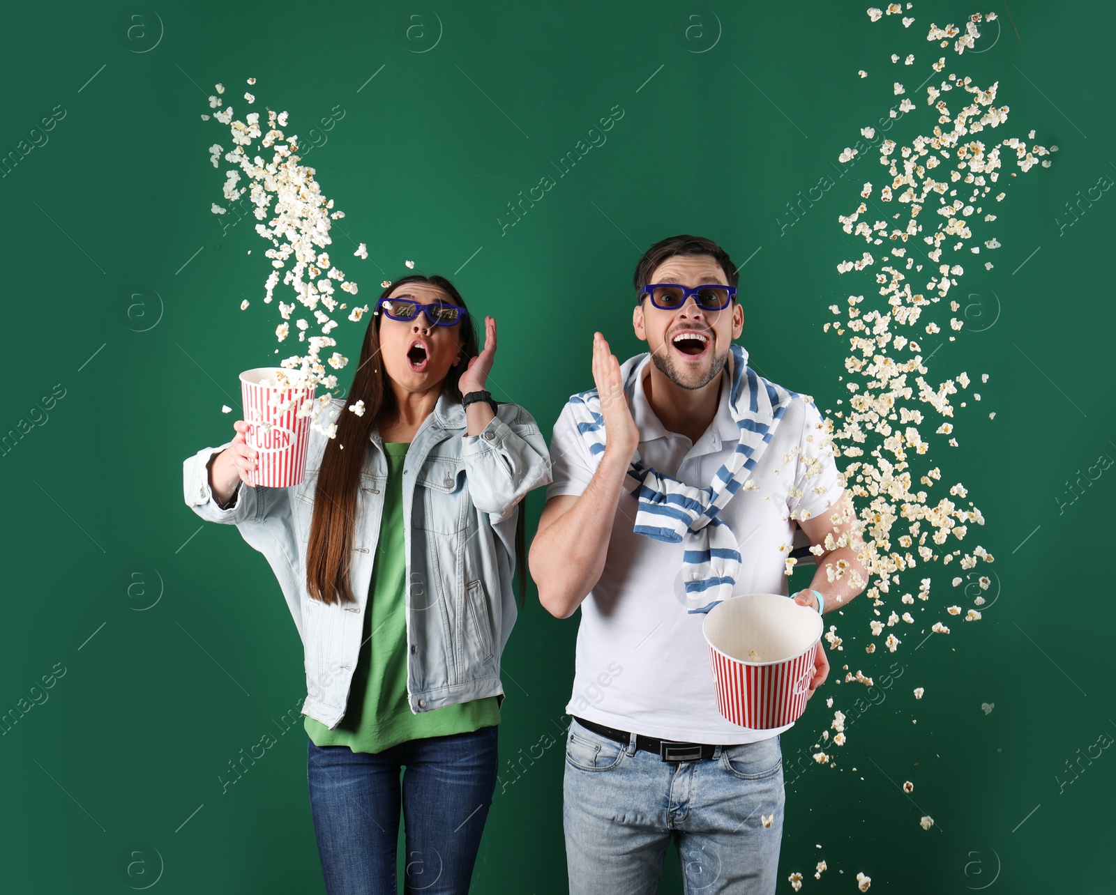 Photo of Emotional couple with 3D glasses throwing popcorn on color background