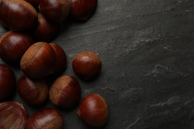 Photo of Roasted edible sweet chestnuts on grey textured table, flat lay. Space for text