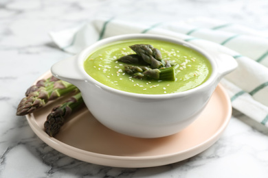 Photo of Delicious asparagus soup served on white marble table