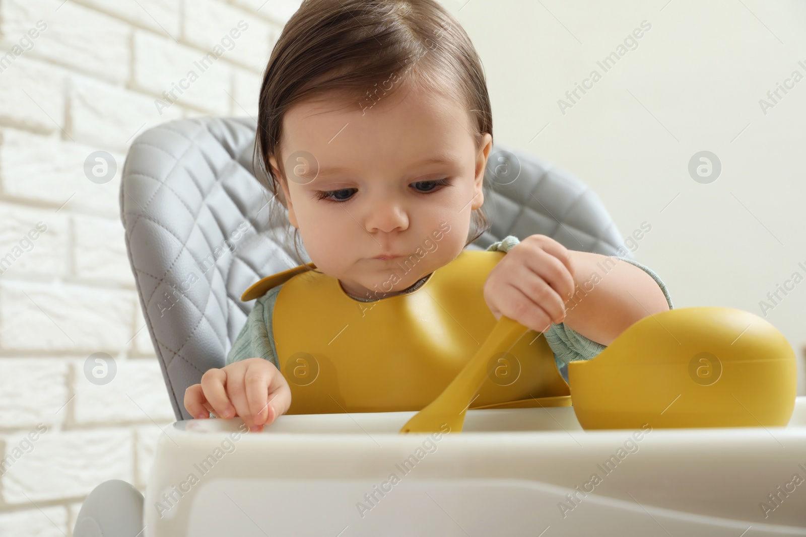 Photo of Cute little baby eating healthy food in high chair indoors