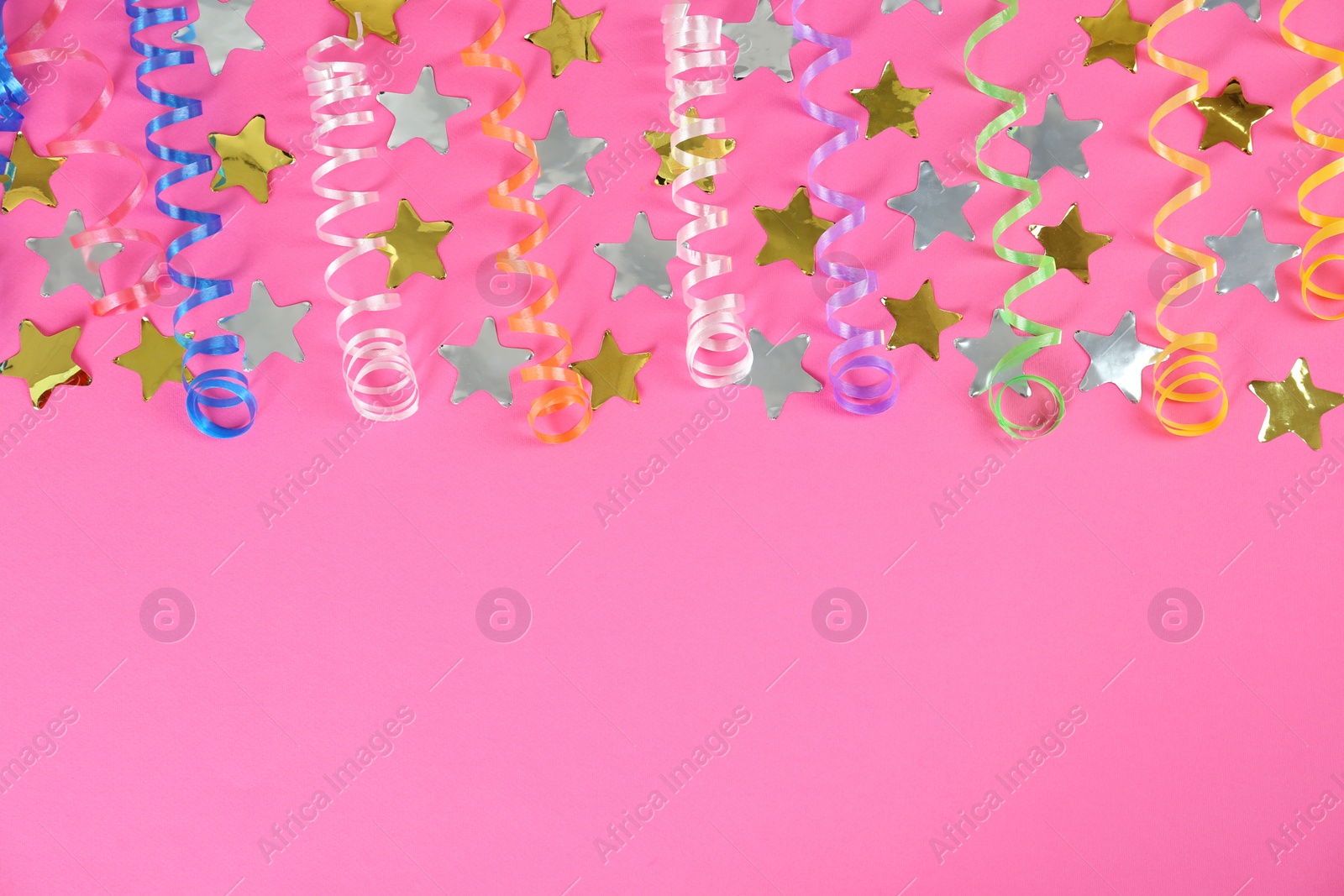 Photo of Colorful serpentine streamers and confetti on pink background, flat lay. Space for text