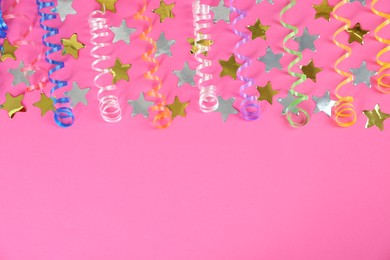 Colorful serpentine streamers and confetti on pink background, flat lay. Space for text