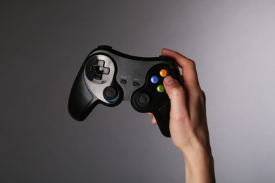 Woman with game controller on grey background, closeup