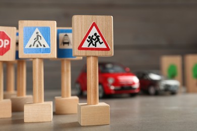Photo of Many different miniature road signs on grey table, closeup with space for text. Driving school