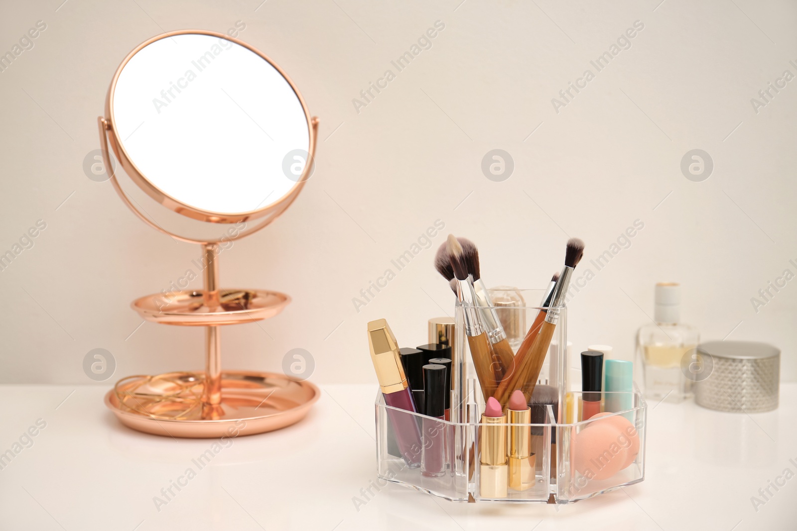 Photo of Makeup cosmetic products and tools in organizer on dressing table