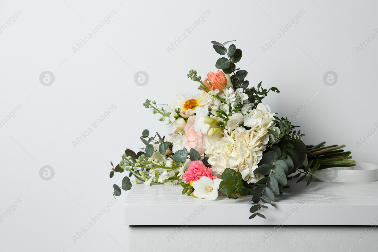 Photo of Bouquet of beautiful flowers on wooden table against white wall. Space for text