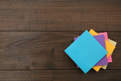 Photo of Stack of colorful stickers on wooden table, top view. Space for text