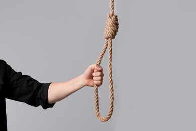 Photo of Man holding rope noose on light background, closeup