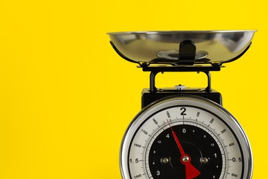Photo of Retro mechanical kitchen scale on yellow background, closeup. Space for text