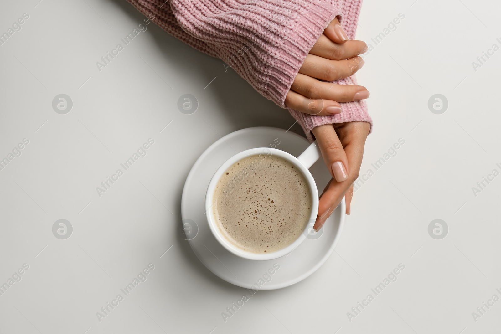 Photo of Woman with cup of coffee at white table, top view
