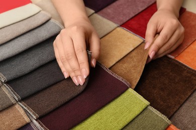 Photo of Woman choosing fabric among multicolored samples, closeup