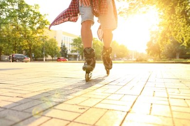 Photo of Young man roller skating outdoors on sunny day, closeup. Recreational activity