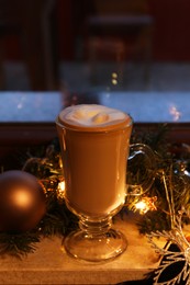 Photo of Glass of delicious hot cocoa and Christmas decoration on windowsill