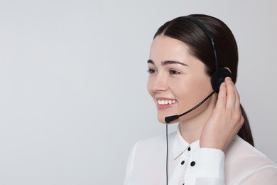Hotline operator with modern headset on light grey background, space for text. Customer support
