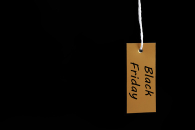 Photo of Blank tag hanging on dark background, space for text. Black Friday concept