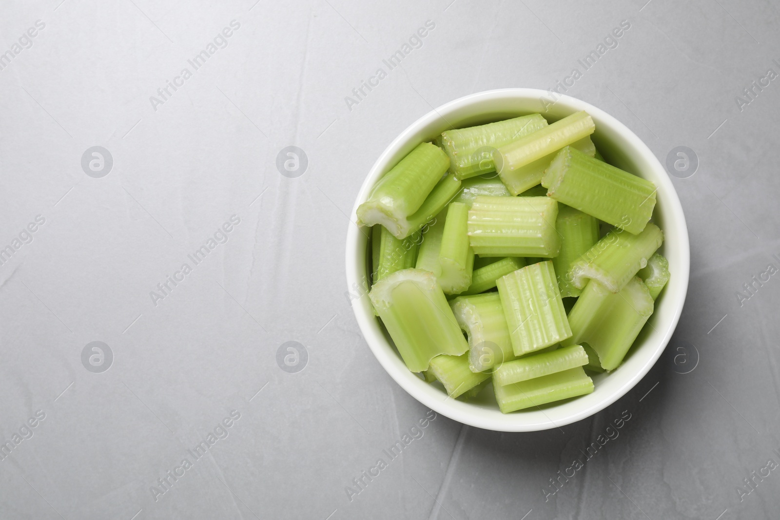 Photo of Fresh green cut celery on light grey table, top view. Space for text