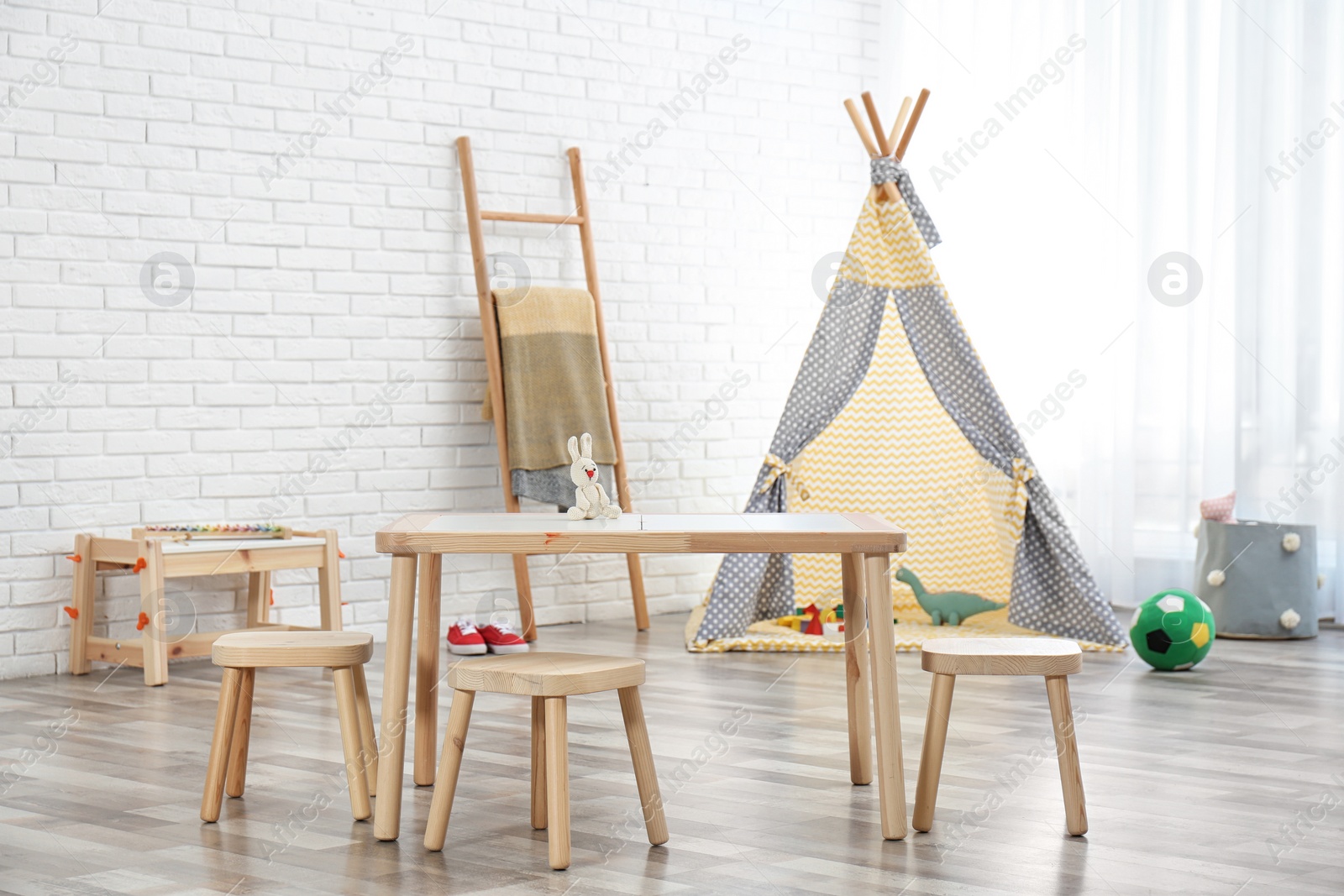 Photo of Cozy kids room interior with table, stools and play tent