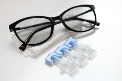 Single dose eye drops, glasses and fabric on white table