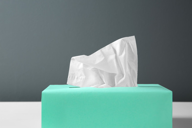 Photo of Box with paper tissues on table against black background, closeup