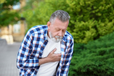 Mature man having heart attack, outdoors