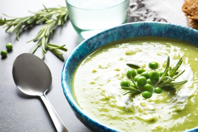 Photo of Fresh vegetable detox soup made of green peas in dish served on table, closeup