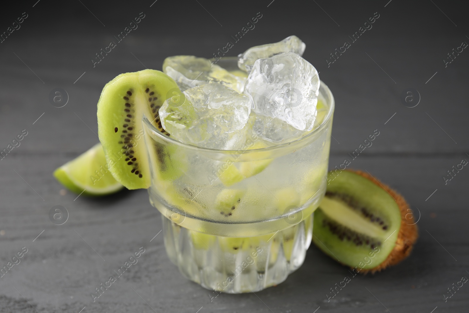 Photo of Glass of refreshing drink and cut kiwi on gray table, closeup