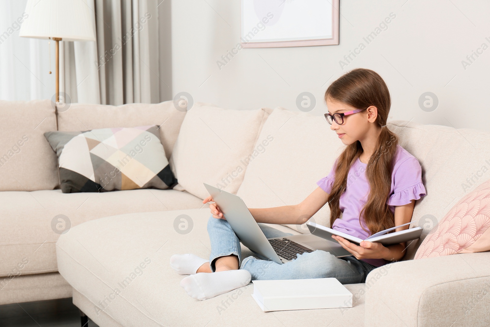 Photo of Girl with laptop and books on sofa at home