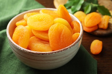 Photo of Bowl of tasty apricots on wooden table, closeup. Dried fruits