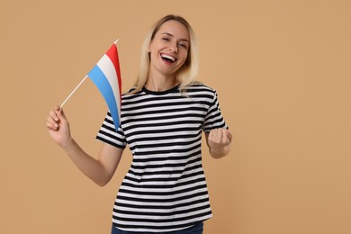 Photo of Happy woman with flag of Netherlands on beige background, space for text