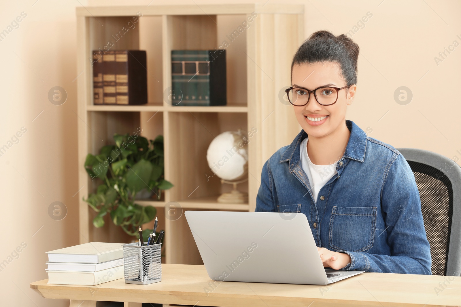Photo of Portrait of smiling African American woman with laptop at wooden table indoors