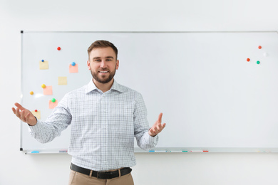 Photo of Portrait of young teacher near whiteboard in classroom. Space for text