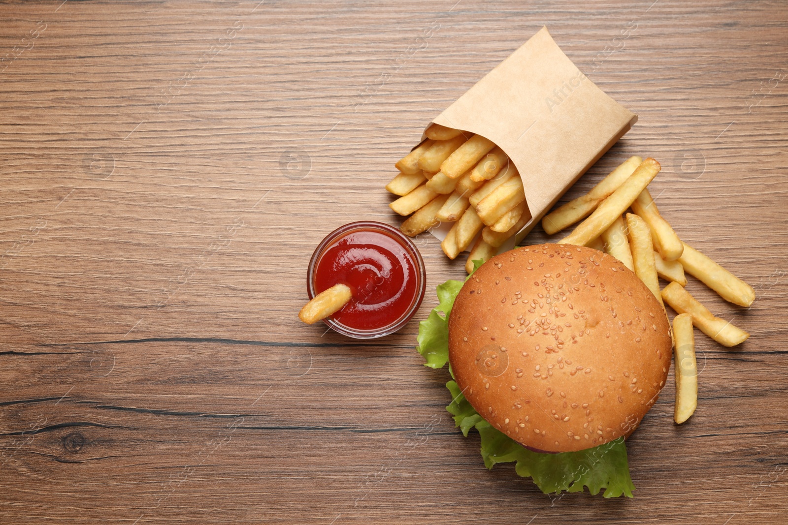 Photo of French fries, tasty burger and sauce on wooden table, flat lay. Space for text