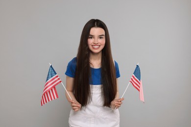 4th of July - Independence Day of USA. Happy girl with American flags on grey background