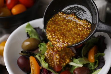 Photo of Pouring tasty vinegar based sauce (Vinaigrette) into bowl with salad, closeup