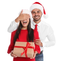 Photo of Lovely young couple in Santa hats with gift box on white background. Christmas celebration