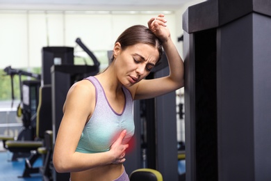 Young woman having heart attack in gym