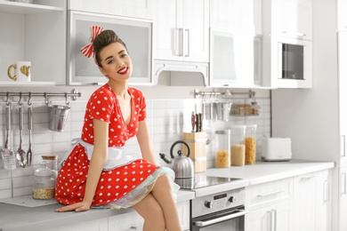 Photo of Funny young housewife sitting on kitchen counter