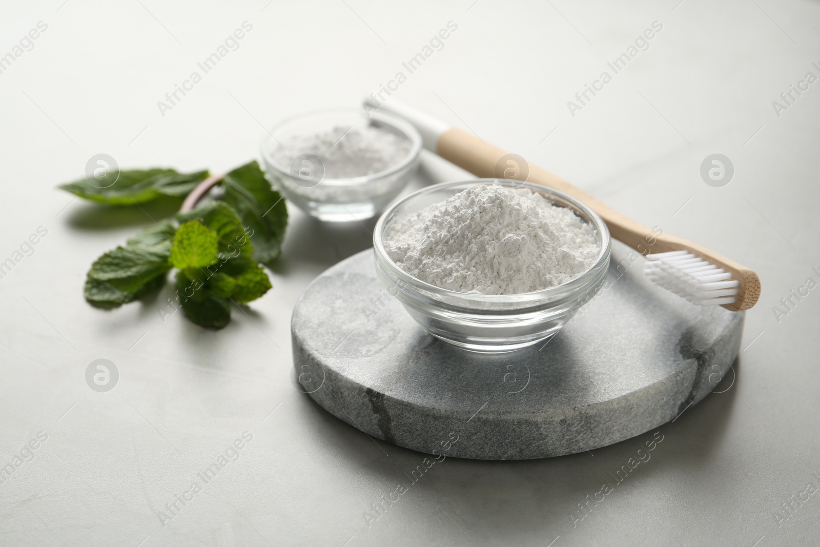 Photo of Tooth powder, brush and mint on grey table